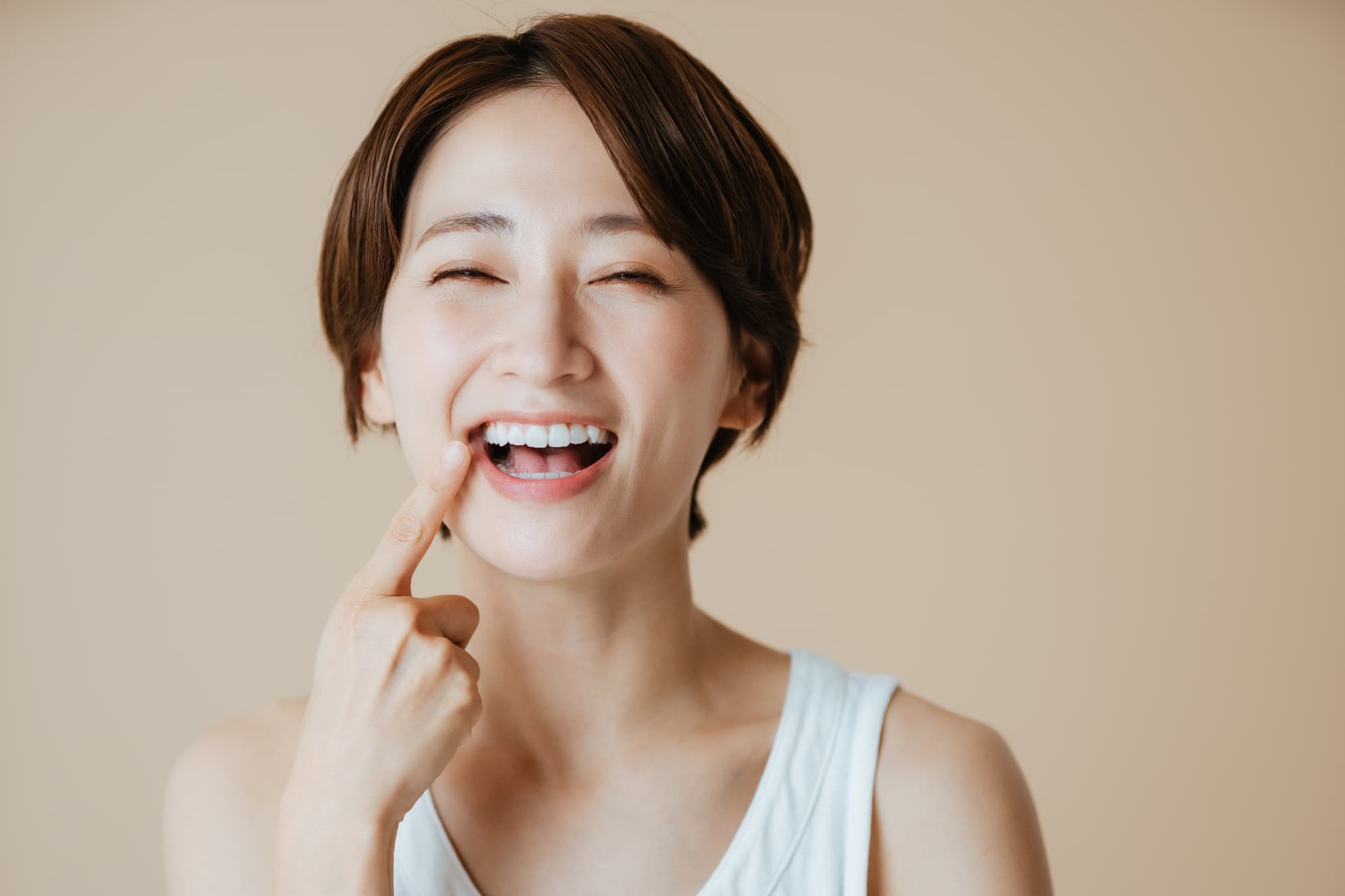 セラミック治療できれいになった歯を指さして笑顔の女性